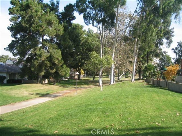 view of property's community with a lawn and fence