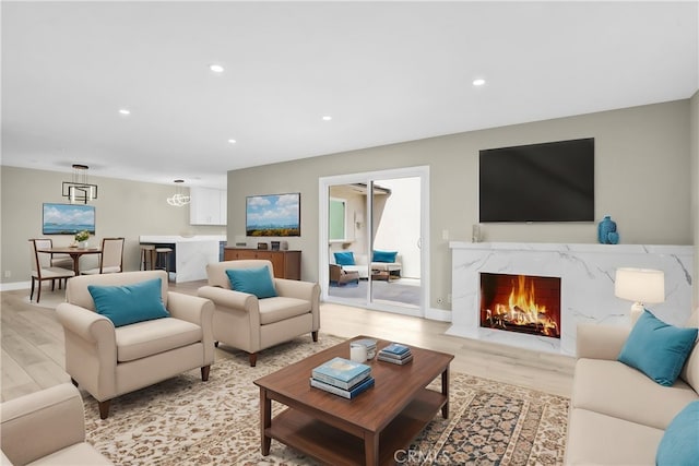 living room with light wood-type flooring, baseboards, recessed lighting, and a premium fireplace