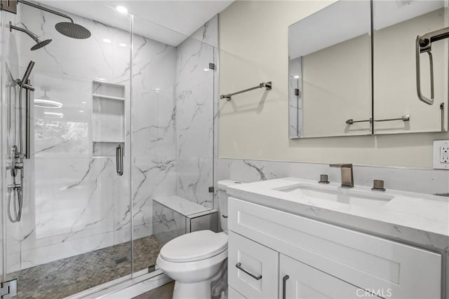 bathroom with toilet, a marble finish shower, tile walls, and vanity