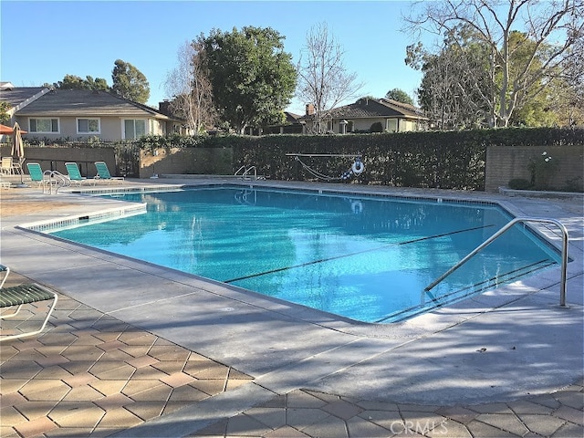 community pool with fence and a patio