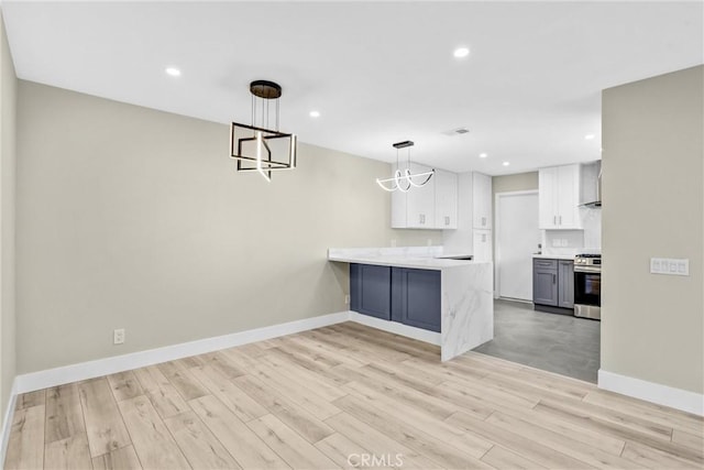kitchen featuring hanging light fixtures, light wood-style flooring, white cabinets, stainless steel gas range, and a peninsula