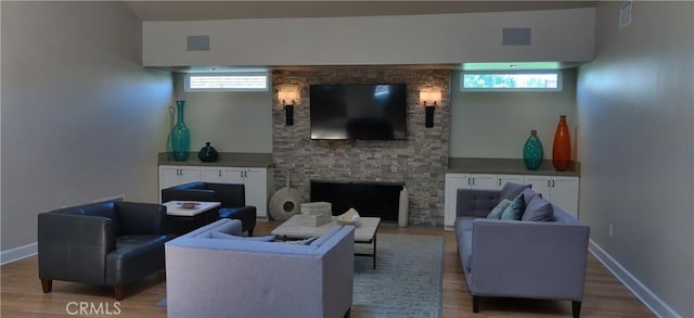 living area with a healthy amount of sunlight, visible vents, a fireplace, and wood finished floors