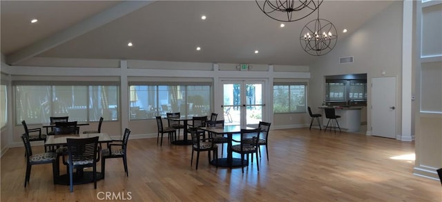 dining space with baseboards, visible vents, an inviting chandelier, light wood-type flooring, and high vaulted ceiling