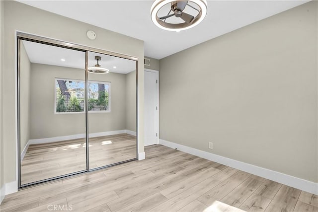 unfurnished bedroom featuring light wood-style flooring, visible vents, baseboards, and a closet