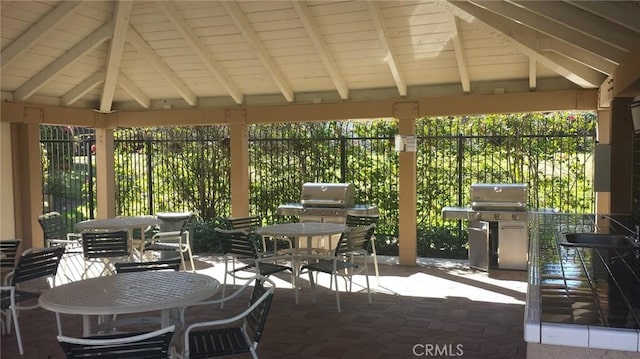 view of patio featuring outdoor dining area, area for grilling, a sink, fence, and a gazebo