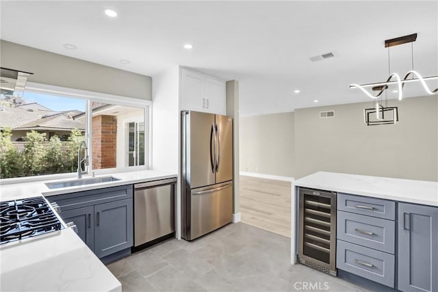 kitchen featuring wine cooler, a sink, visible vents, hanging light fixtures, and appliances with stainless steel finishes