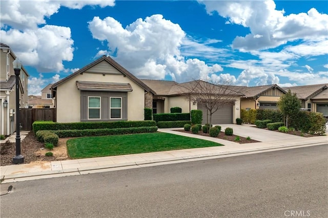 view of front facade with an attached garage, fence, driveway, stucco siding, and a front yard