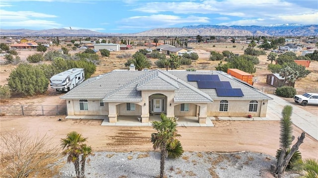 view of front of house with stucco siding, a mountain view, and roof mounted solar panels