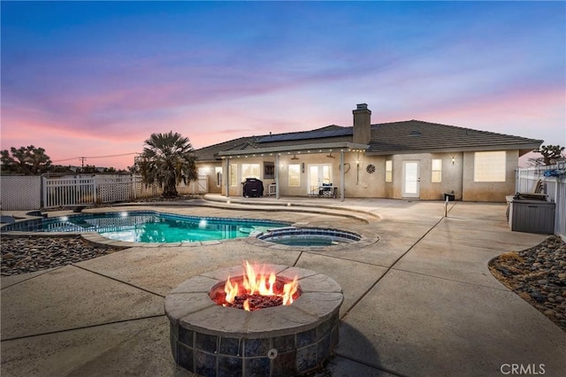 view of pool with a patio area, a pool with connected hot tub, fence, and a fire pit