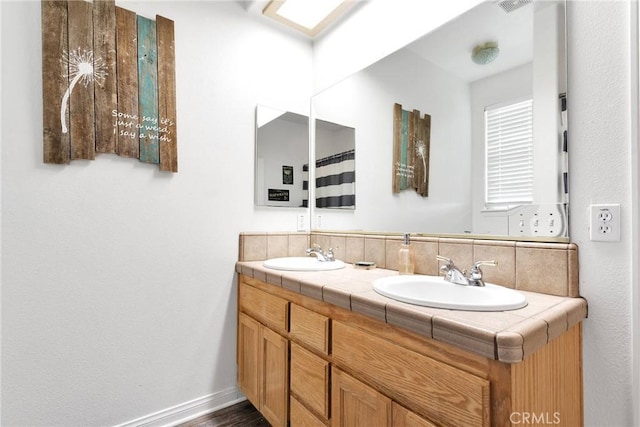 bathroom with double vanity, a sink, and baseboards