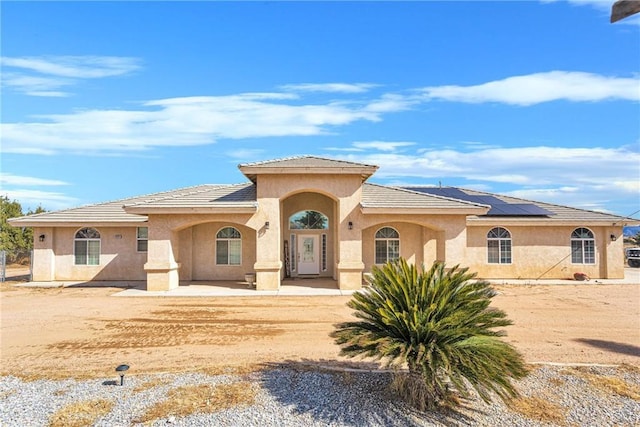 mediterranean / spanish-style house featuring stucco siding and roof mounted solar panels