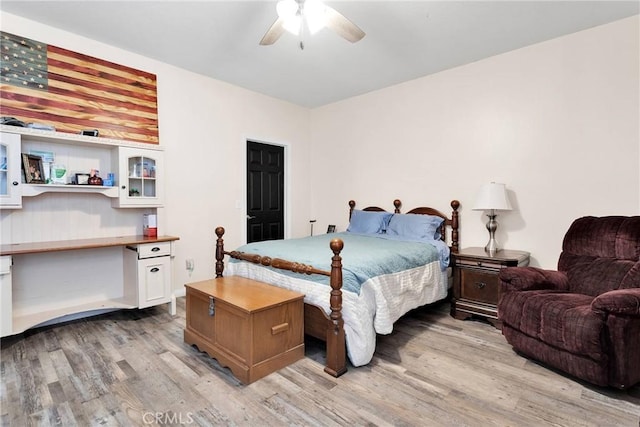 bedroom featuring light wood-type flooring, built in study area, and ceiling fan