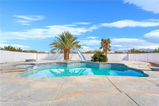 view of pool featuring a patio, a water slide, a fenced backyard, and a pool with connected hot tub