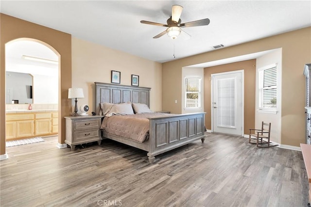 bedroom featuring baseboards, connected bathroom, visible vents, and wood finished floors