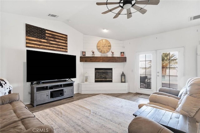 living room with lofted ceiling, visible vents, and wood finished floors