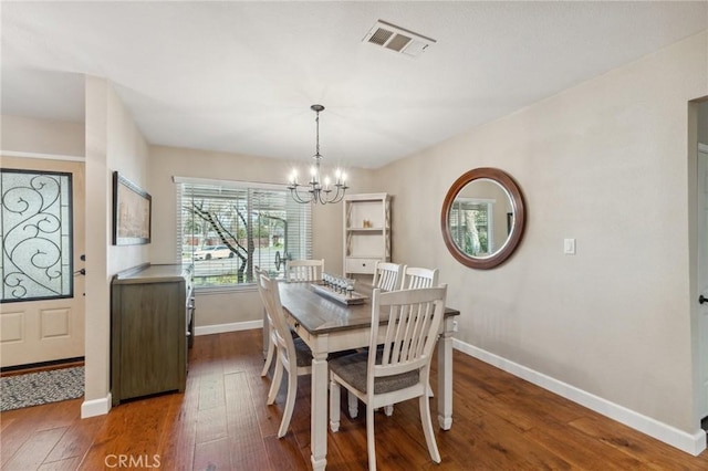 dining space featuring dark wood-style flooring, visible vents, a notable chandelier, and baseboards