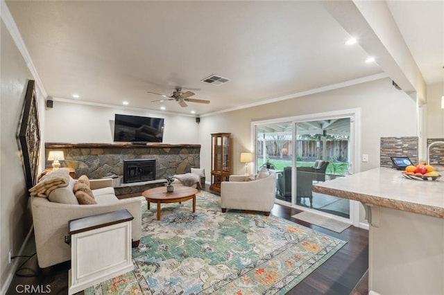 living room featuring recessed lighting, a fireplace, visible vents, dark wood-style floors, and crown molding