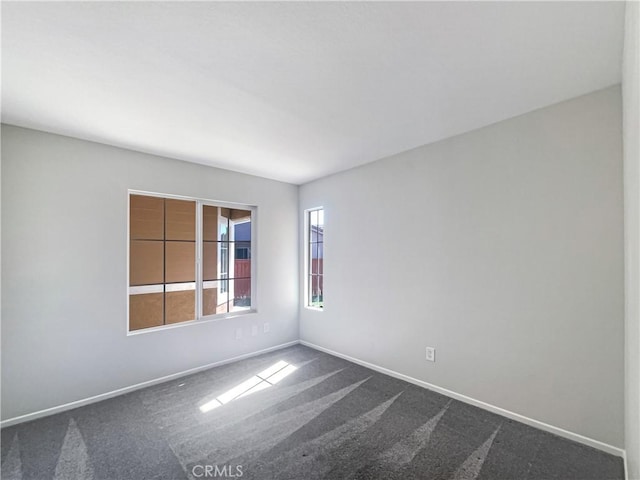 unfurnished room featuring carpet and baseboards