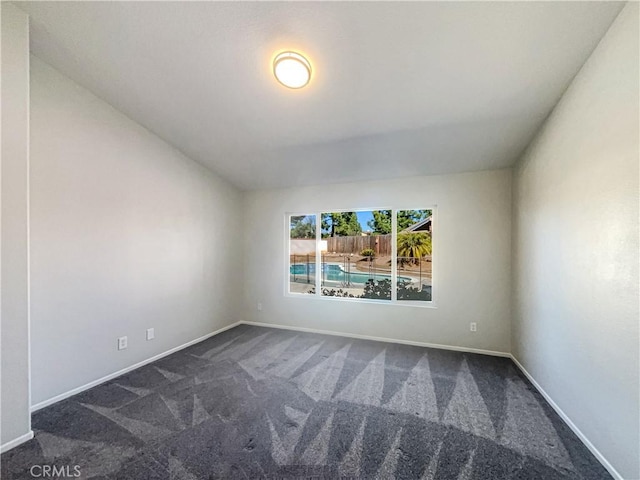 unfurnished room featuring dark carpet and baseboards