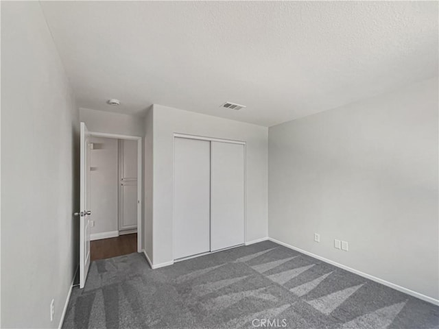 unfurnished bedroom with a textured ceiling, a closet, visible vents, and baseboards