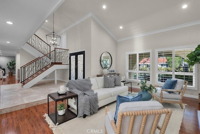 living area featuring stairway, ornamental molding, wood finished floors, a high ceiling, and a notable chandelier