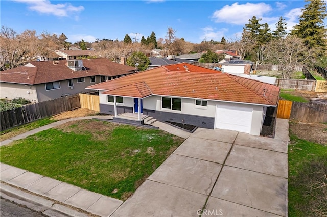 view of front of house with concrete driveway, fence, a residential view, a tiled roof, and a front lawn