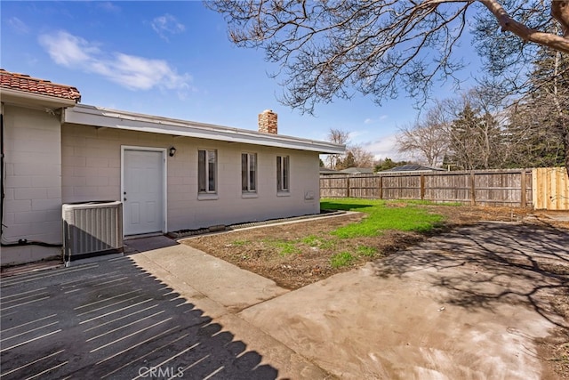 355 French St, Willows, CA 95988 - rear view of house with central air condition unit, a chimney, fence, and concrete block siding