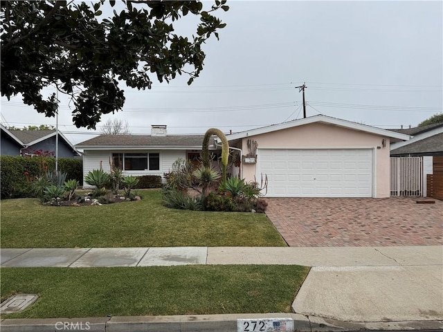 single story home featuring a garage, stucco siding, decorative driveway, and a front yard