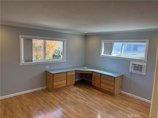 unfurnished office featuring built in study area, crown molding, a textured ceiling, and light wood finished floors