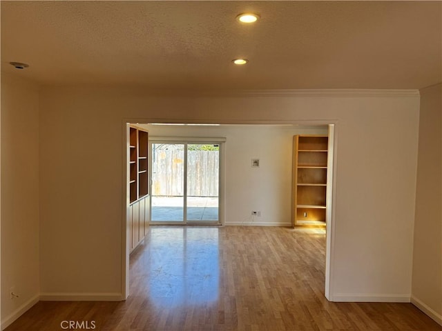 unfurnished room featuring light wood-style floors, baseboards, and a textured ceiling