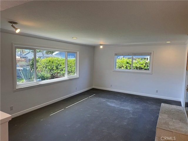 spare room with plenty of natural light, concrete floors, and baseboards