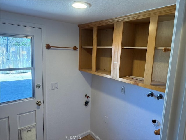 laundry room with a textured ceiling and baseboards