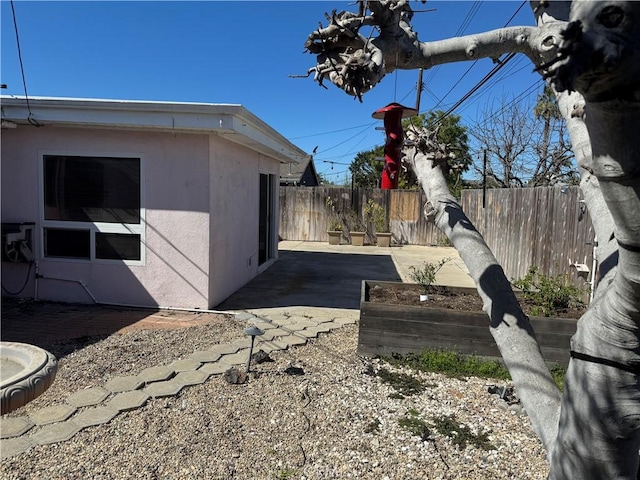 view of side of property with a patio, fence, and stucco siding