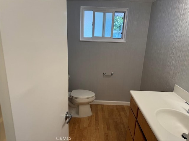 bathroom with toilet, baseboards, wood finished floors, and vanity