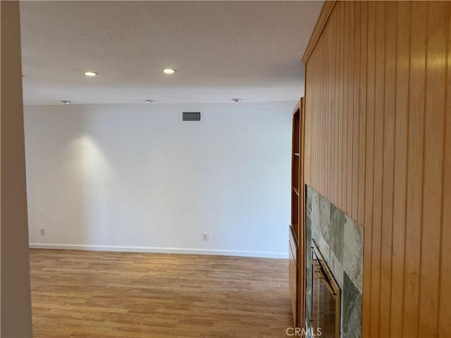 unfurnished living room featuring light wood-style floors, a fireplace, visible vents, and a textured ceiling