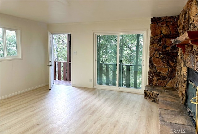 living room with light wood-style floors, a fireplace, baseboards, and crown molding