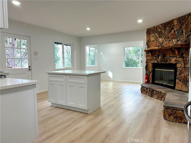 kitchen with light wood-style flooring, open floor plan, light countertops, a fireplace, and white cabinetry