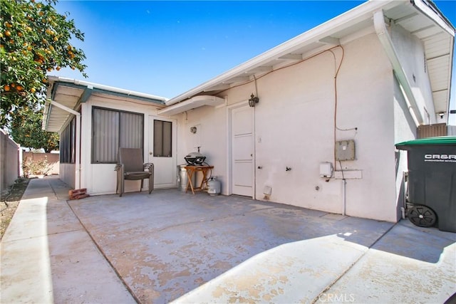 view of property exterior with stucco siding, a patio, and fence