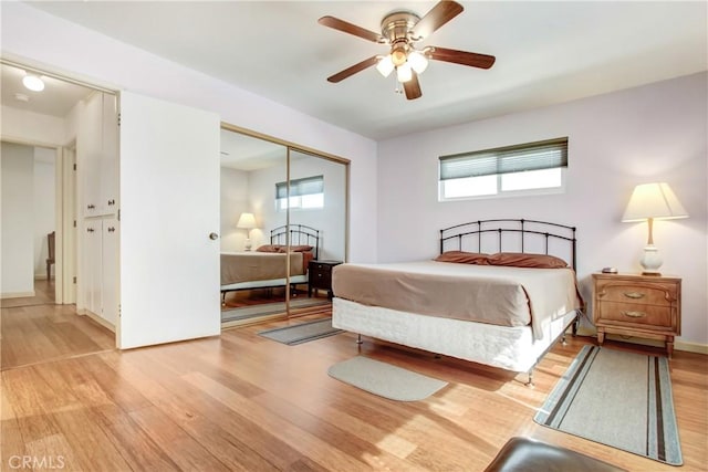 bedroom with light wood-style flooring, ceiling fan, and a closet