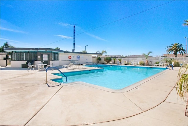 pool with a patio area and fence