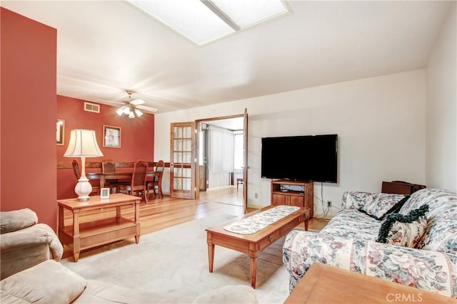 living room featuring a skylight, visible vents, ceiling fan, and light wood finished floors