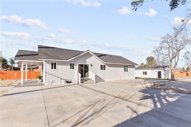 rear view of house featuring entry steps and fence