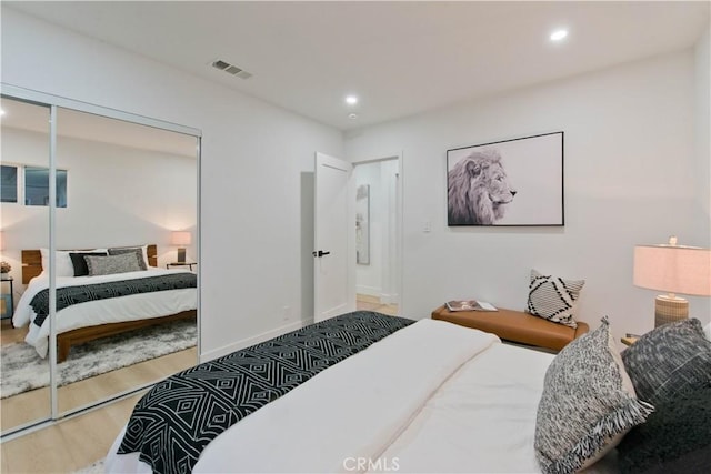 bedroom with a closet, visible vents, wood finished floors, and recessed lighting