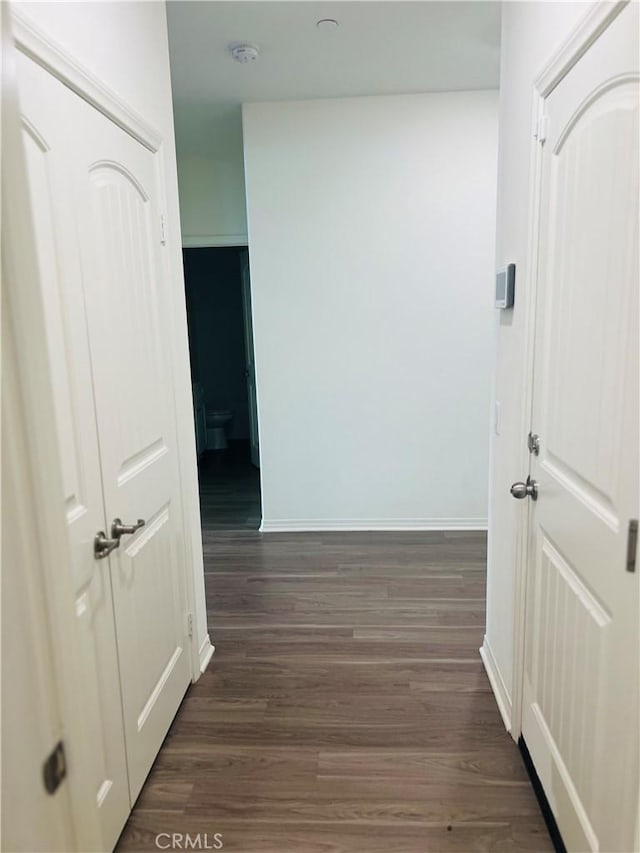 hall with dark wood-type flooring and baseboards