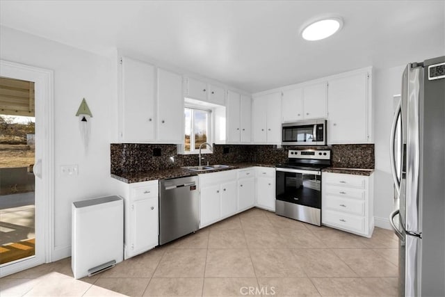 kitchen with dark stone counters, appliances with stainless steel finishes, a sink, and white cabinets