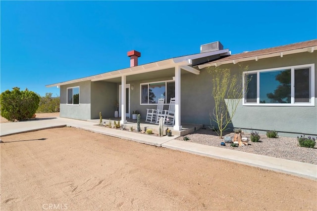 ranch-style home featuring covered porch and stucco siding