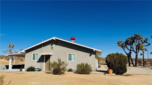 back of property featuring an attached carport and stucco siding