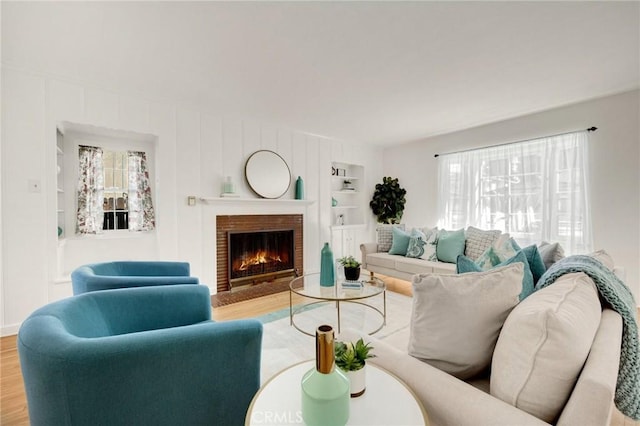 living room featuring built in features, a brick fireplace, and wood finished floors