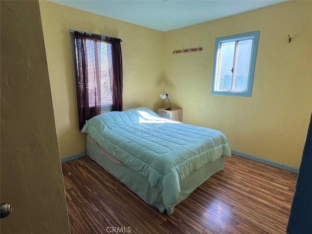 bedroom with multiple windows, baseboards, and wood finished floors