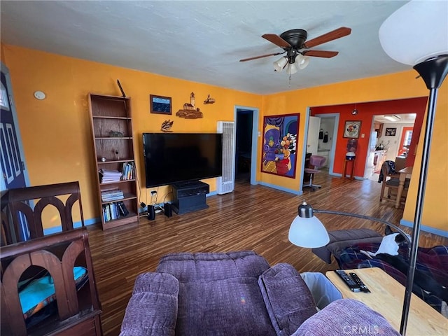 living room featuring wood finished floors, a ceiling fan, and baseboards